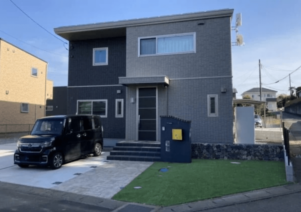 茨城県守谷市の新築外構全体。ガビオンの土留めと人工芝が映える、傾斜地を活かしたナチュラルな門まわり。