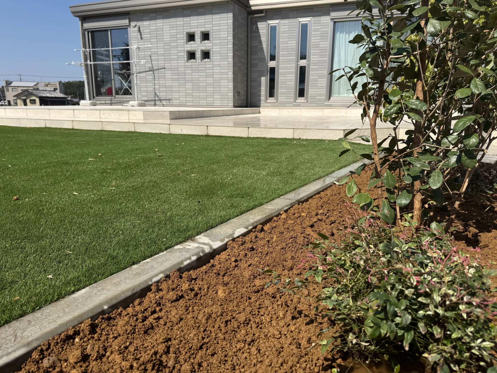 バーベキューやプール遊びに最適。タイルデッキから広がる一年中緑が美しい人工芝のお庭