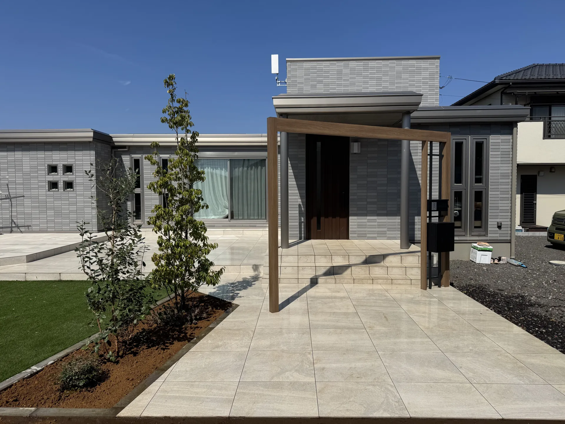 プラスGのアーチをくぐり、タイルアプローチからタイルデッキ、人工芝へと続く開放的な外構デザイン