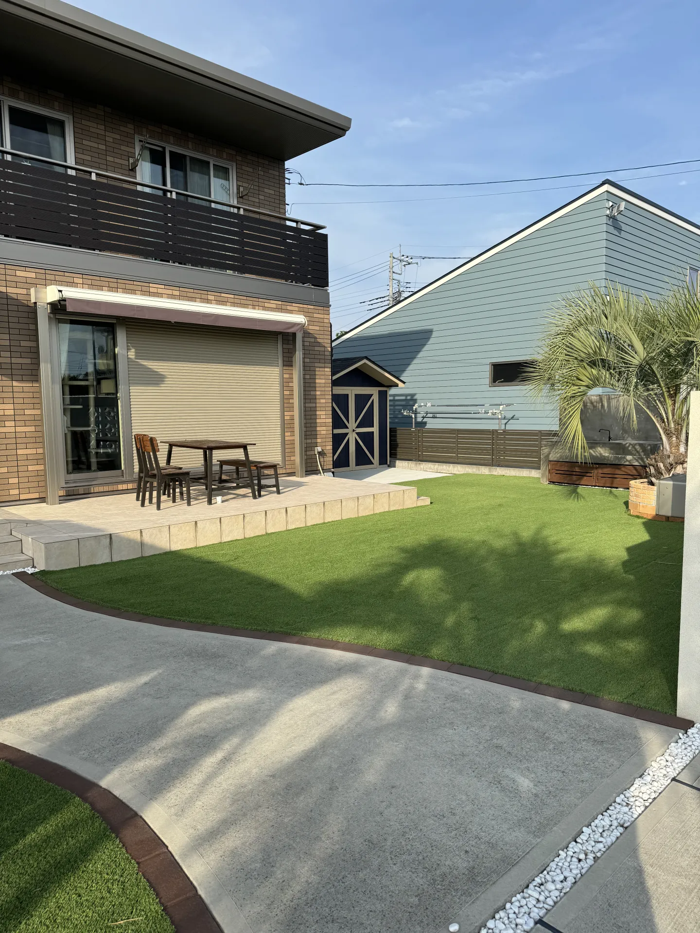 塗り替えで一新したアプローチ横のレンガと、人工芝や目隠しで使い勝手が良くなったリビング前の空間